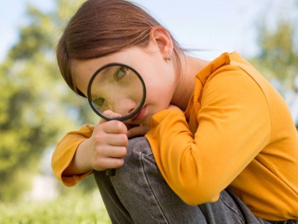 Ein Mädchen schaut durch eine Lupe